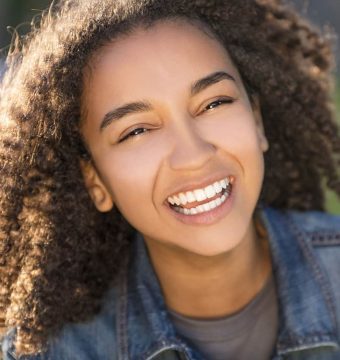 Outdoor portrait of beautiful happy mixed race African American girl teenager female young woman smiling laughing with perfect teeth